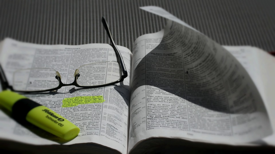 A picture of a Bible with glasses and a marker on it